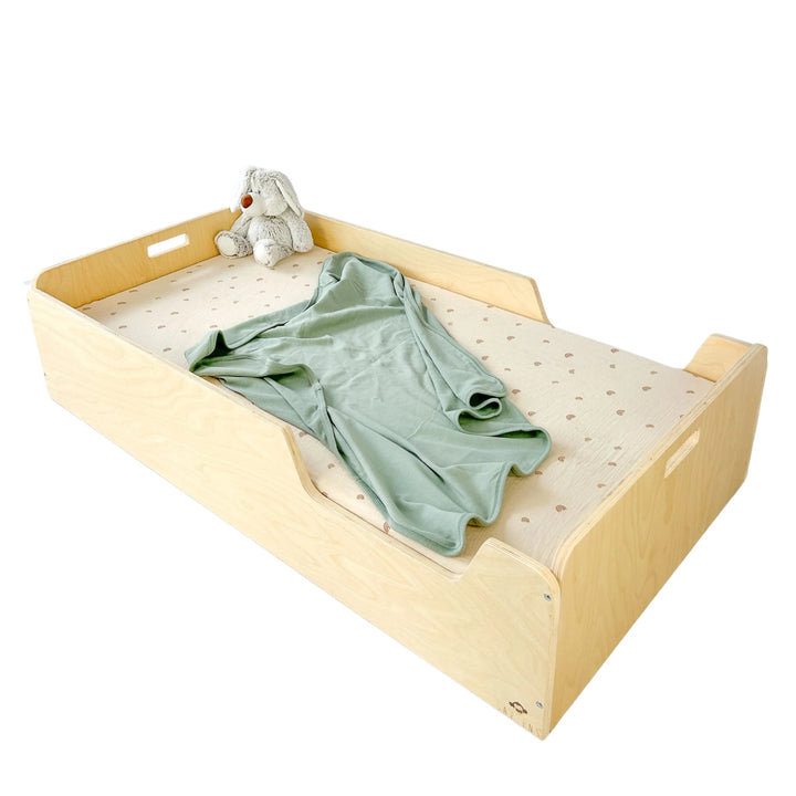 Wooden crib with a green blanket and stuffed toy on a white background, featuring the brand 'CRIB'.