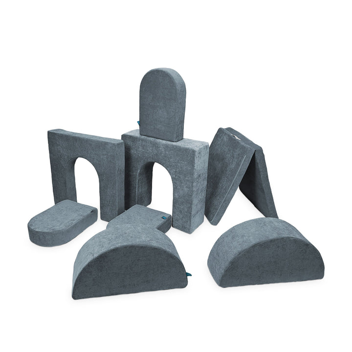 A set of gray modular foam pieces designed for creative play, including arches, steps, and other shapes.