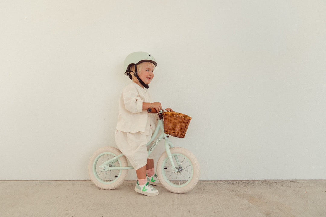 Toddler in a helmet riding the Banwood First Go balance bike