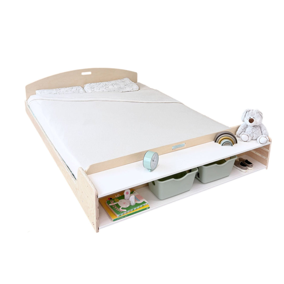 Wooden bed with mattress, toys, and books on a white background