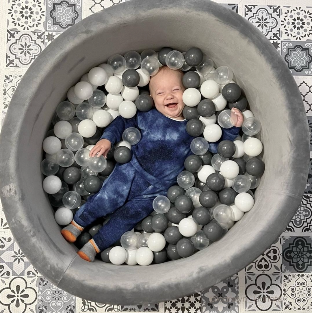 Kids Smiling Inside A Grey Ball Pit