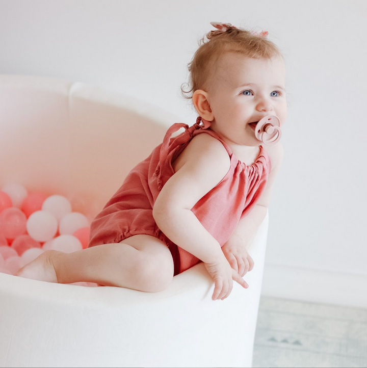 Baby Playing And Smiling In A White Ball Pit