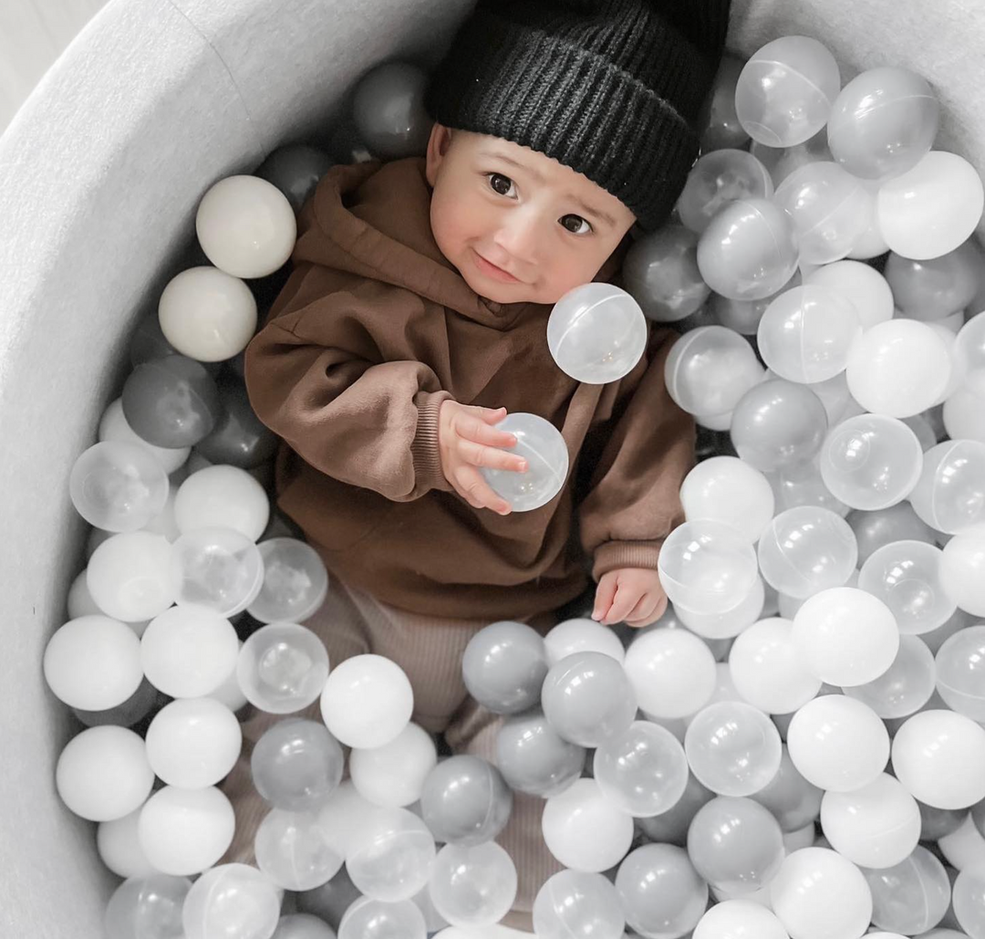 Toddler Playing In A White Ball Pit