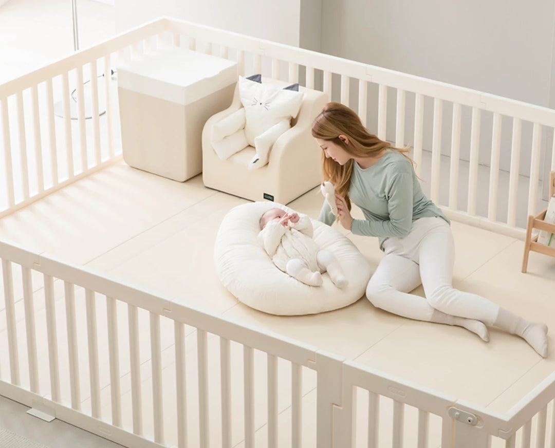 Woman sitting on a white crib with a baby and a white bean bag