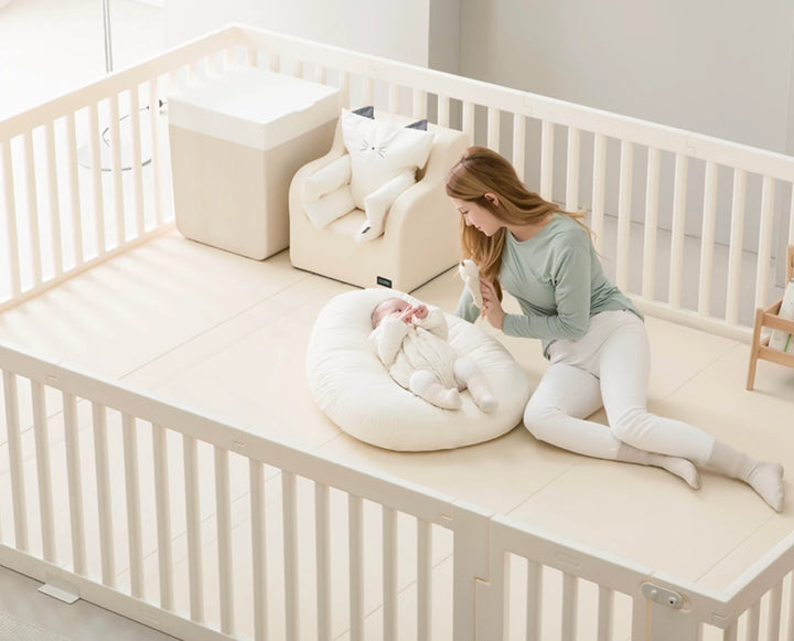 Woman sitting on a white crib with a baby and a white bean bag
