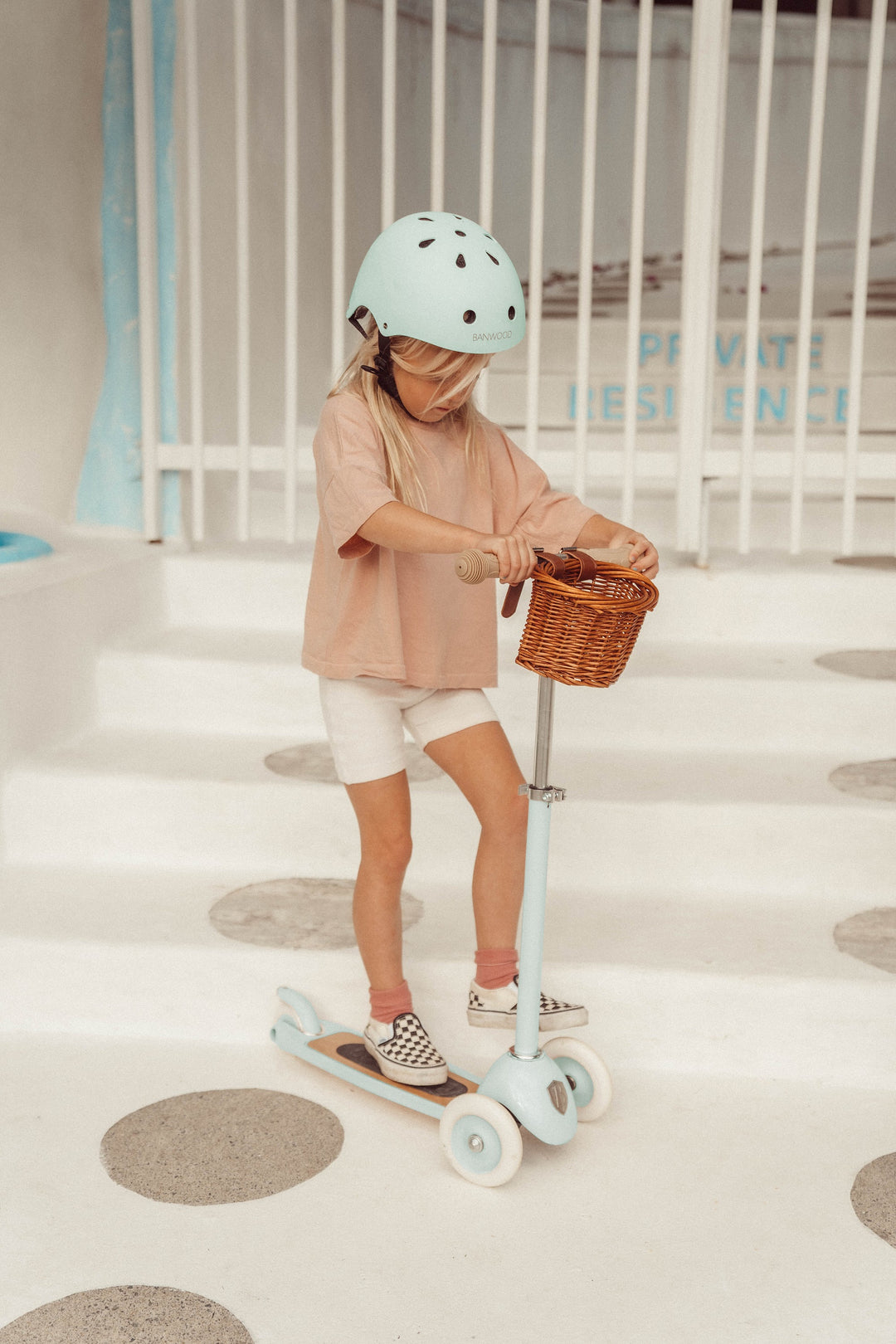 Child in a helmet with the Banwood Vintage Scooter in Pale Mint