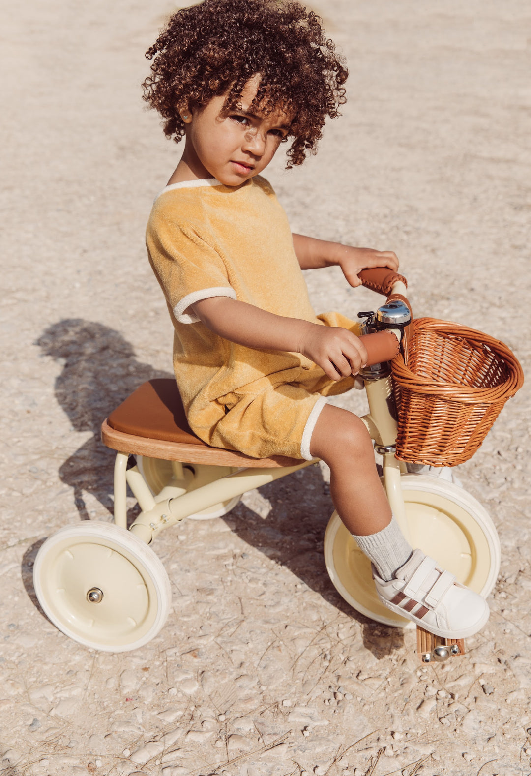 Toddler riding the Banwood Vintage Trike in Cream outdoors