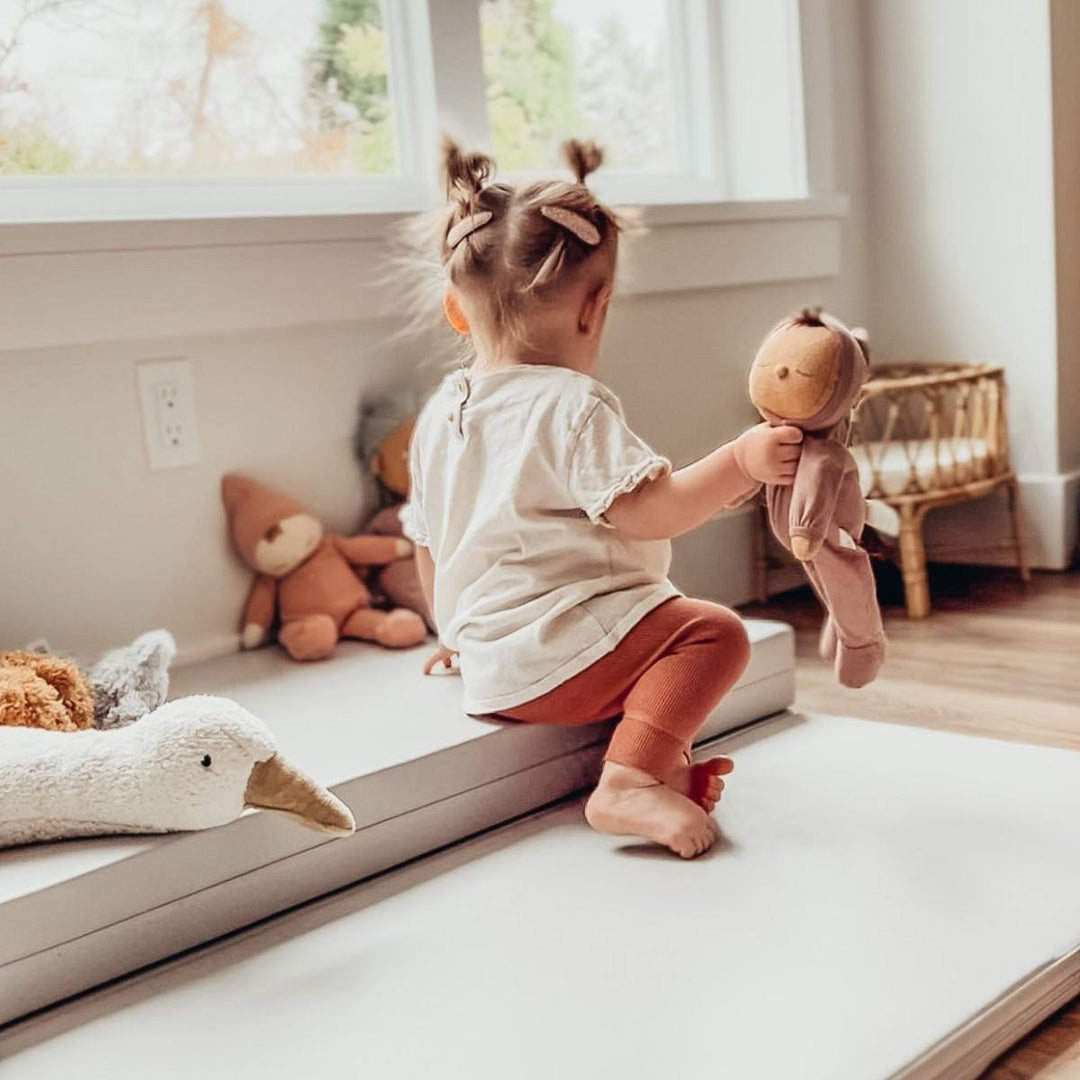 toddler playing with soft toys on a playmat